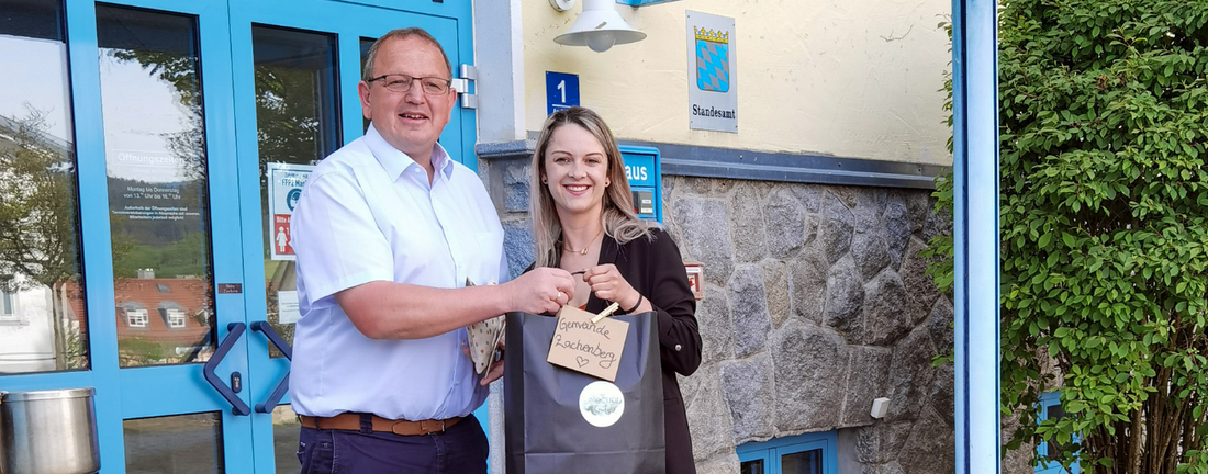 Bürgemeister Hans Dachs von Zachenberg mit Inhaberin Silvia Aigner von Selectionkreativ bei der Übergabe der Babygeschenke für die Neugeborenen in Zachenberg